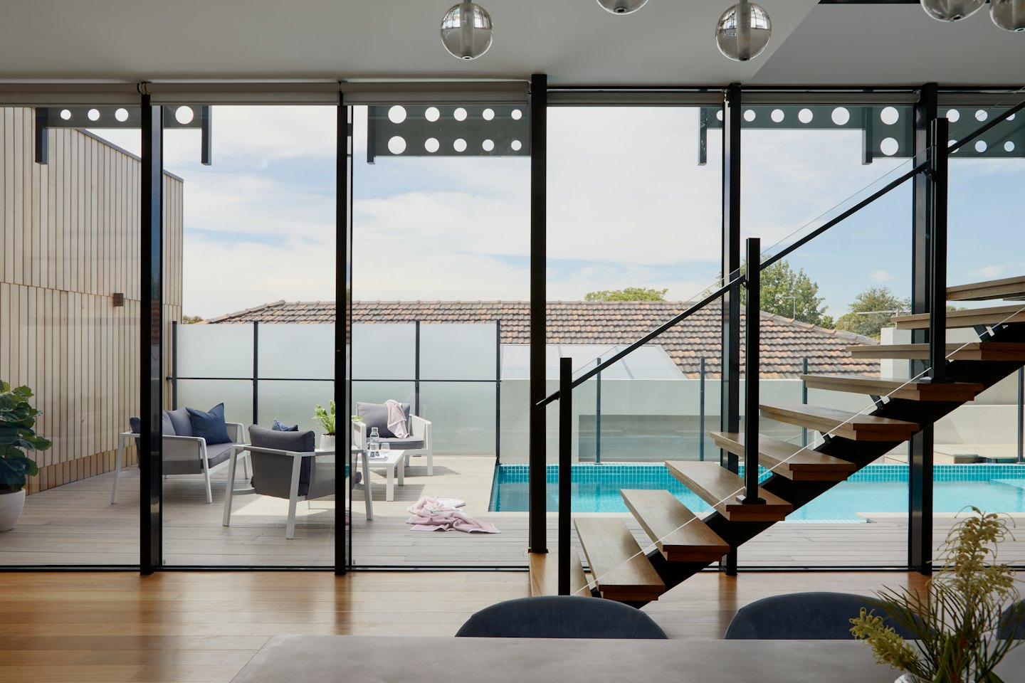 Modern home interior with pool and patio visible through glass doors.